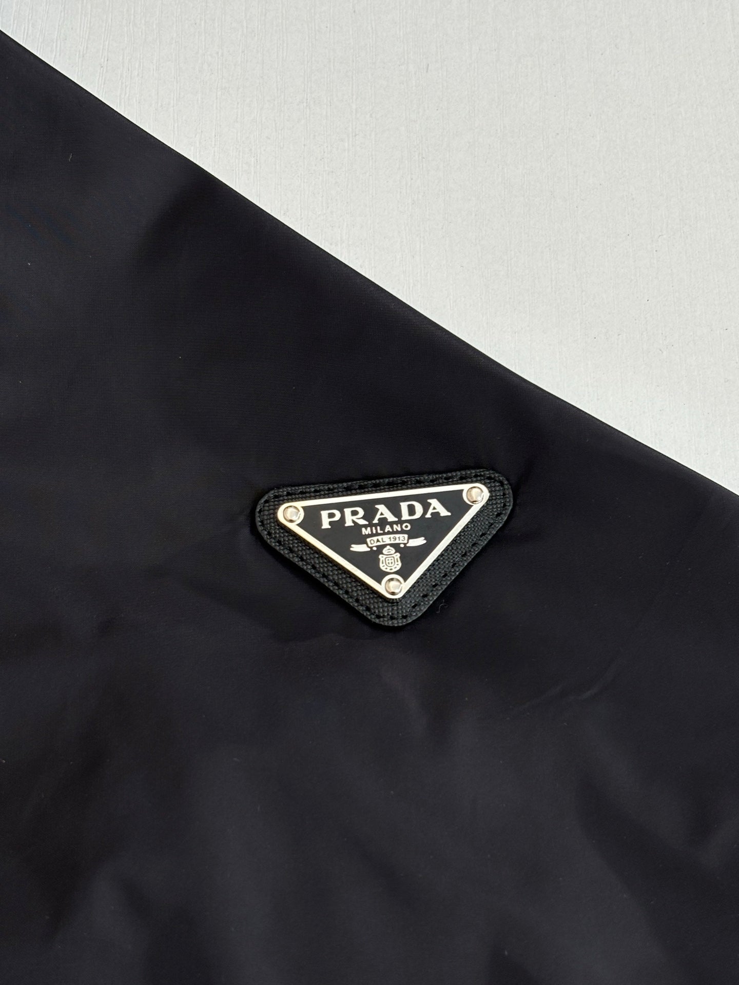 Prada logo triangle patch on dark outer fabric of hooded jacket