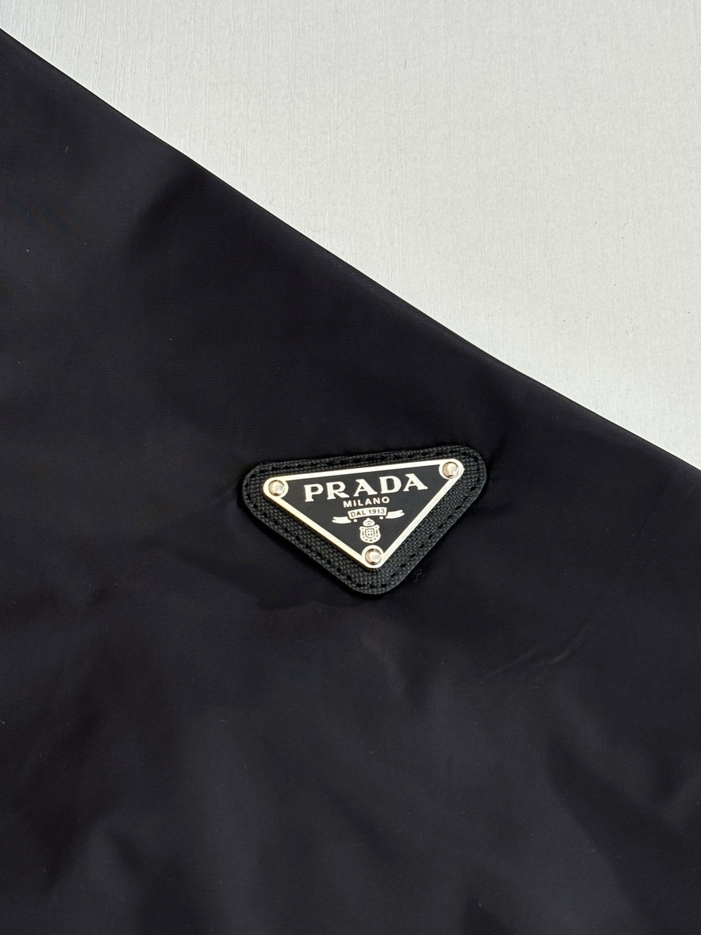 Prada logo triangular patch on black puffer jacket chest