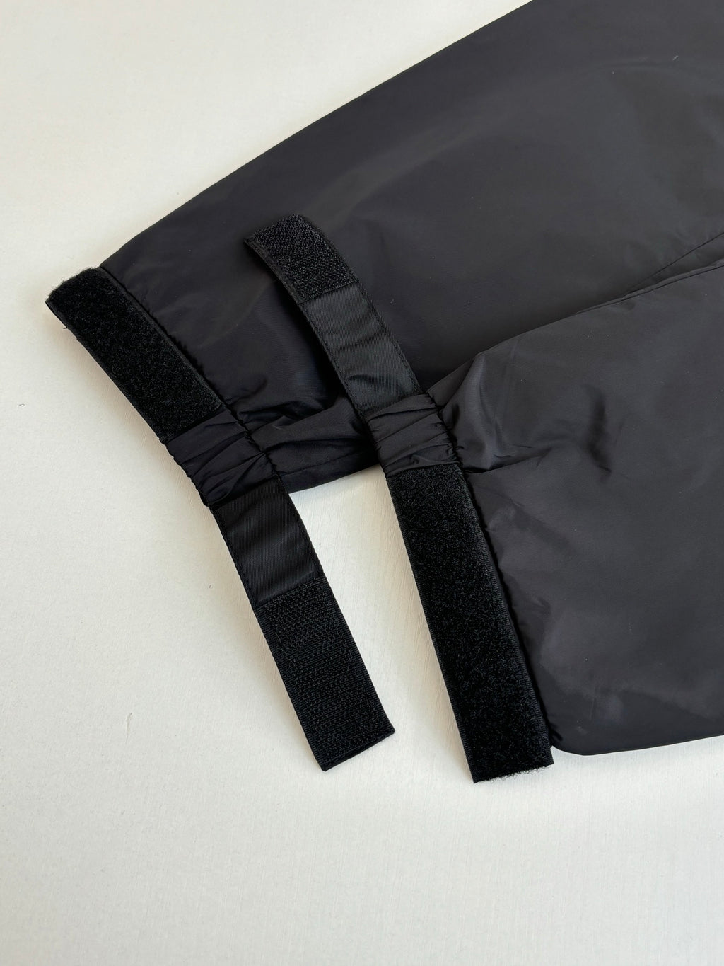 Prada jacket hem detail with black webbing tabs and gathered fabric edge