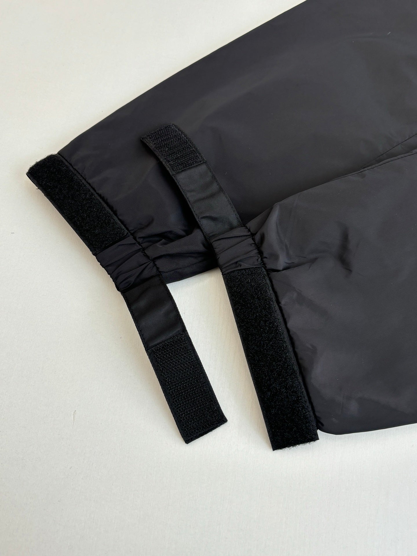 Prada jacket hem detail with black webbing tabs and gathered fabric edge