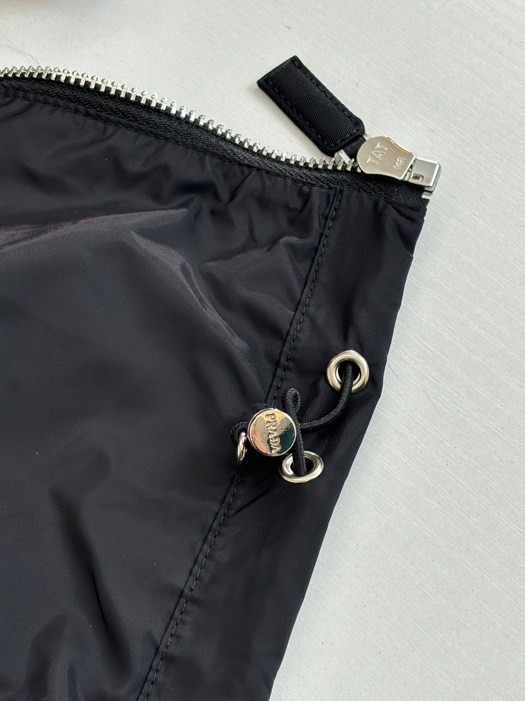Prada jacket waist detail with zipper tab and snap-ring hardware