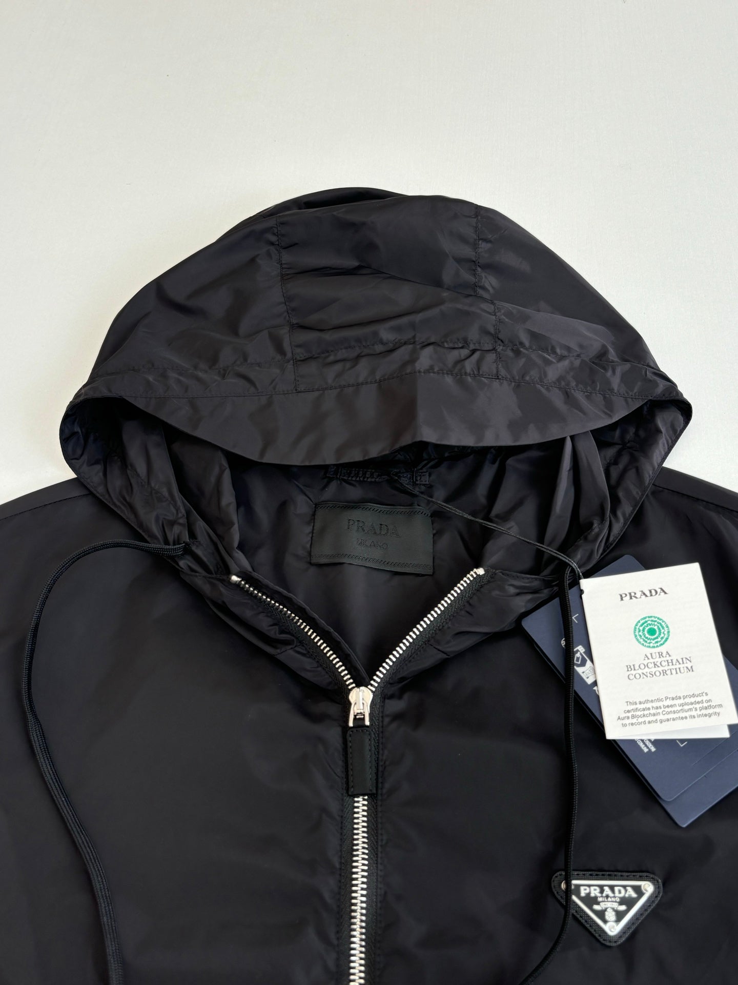 Prada hooded jacket close-up with silver-tone zipper and triangular logo patch