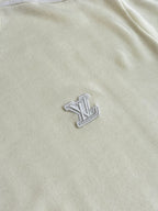 Cream sweater front with raised embroidered LV-style emblem near chest