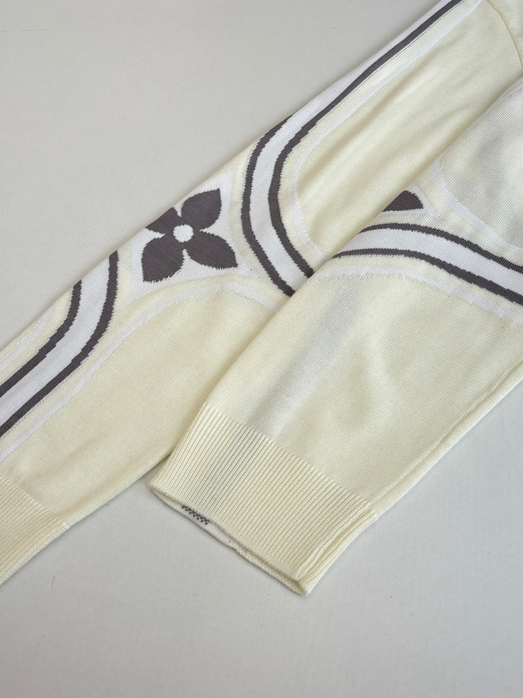 Cream sweater sleeve with navy-and-white striped band at cuff