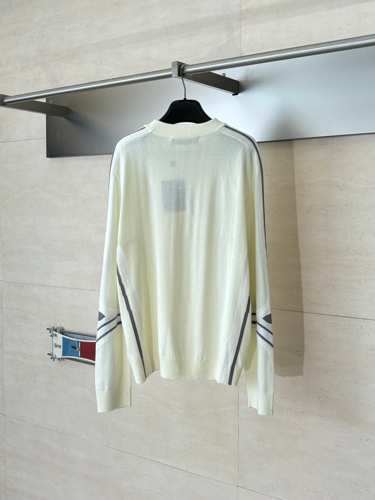 Cream long-sleeve sweater, back view with ribbed cuffs and striped sleeve details