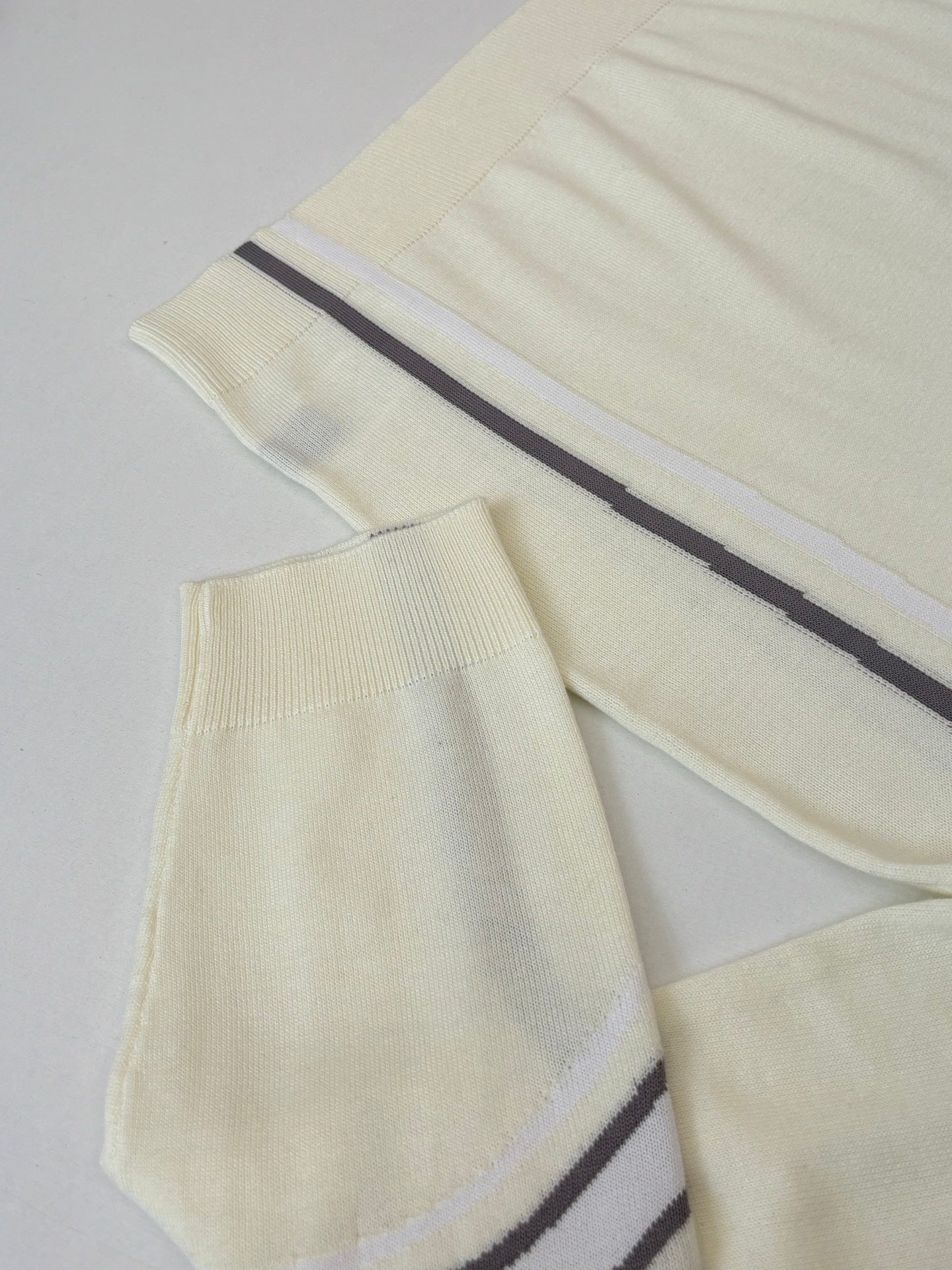 Cream knit sweater sleeves and body with navy side stripes on ribbed cuffs