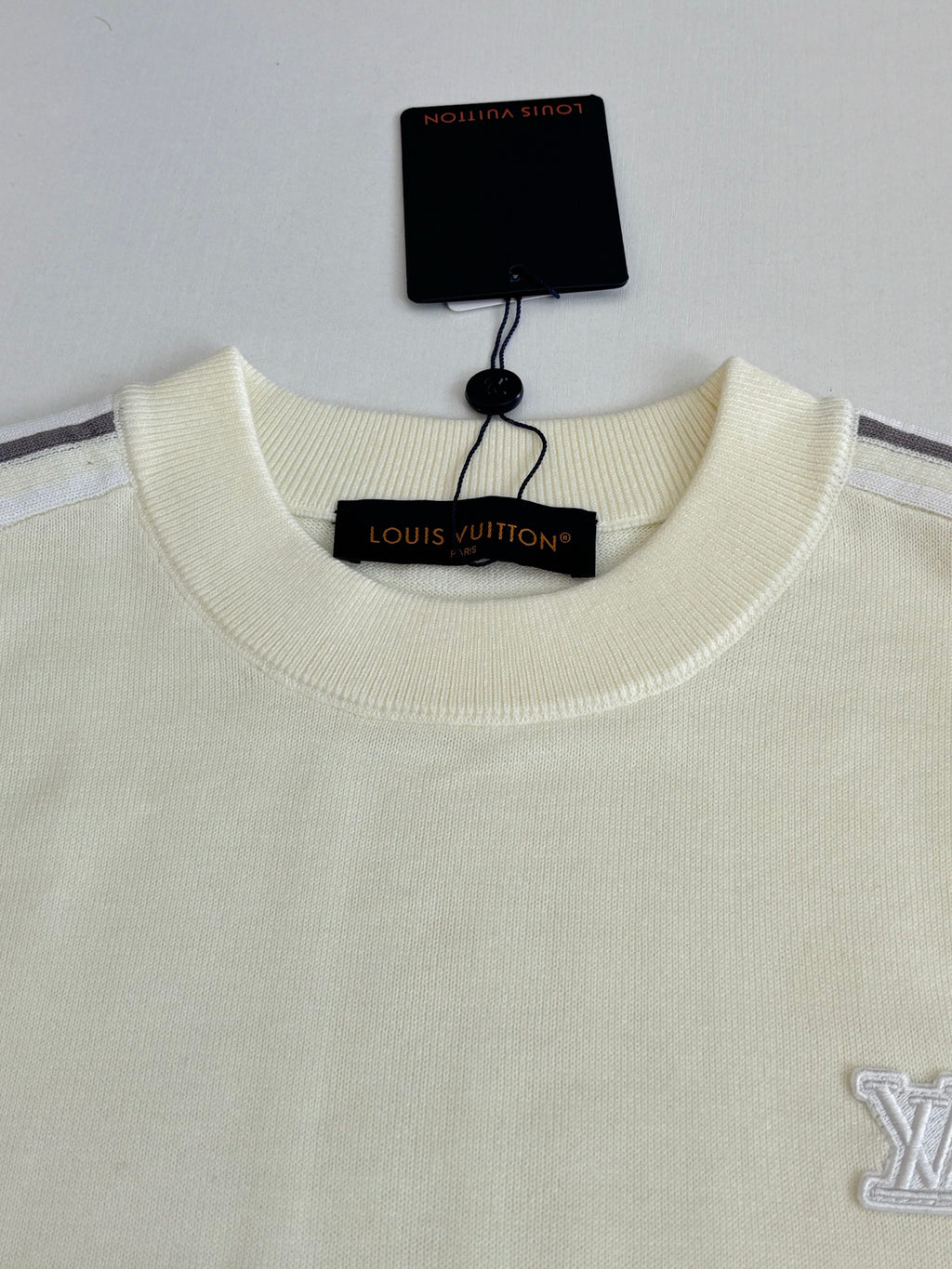 Cream crewneck sweater with embroidered side logo and hanging neck label