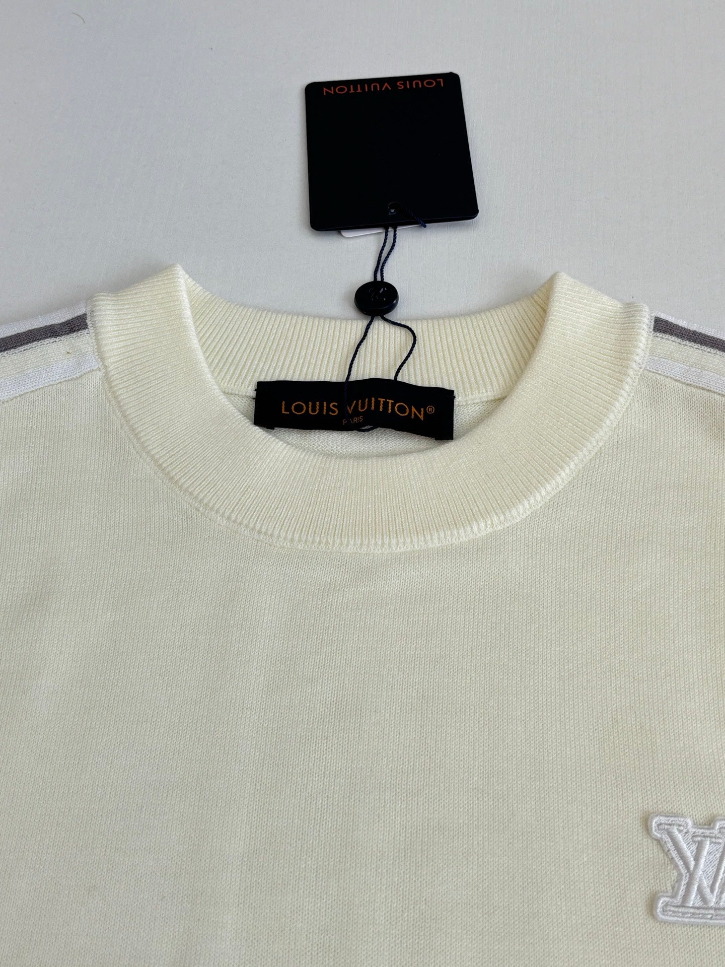 Cream crewneck sweater with embroidered side logo and hanging neck label