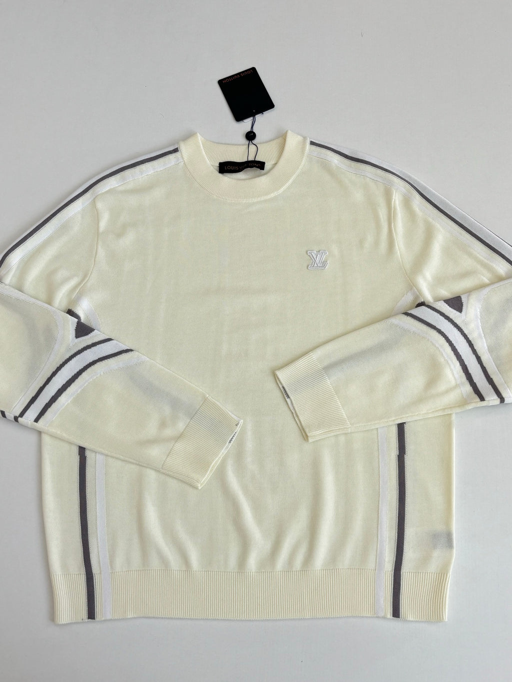 Cream long-sleeve sweater with small chest logo and navy-striped shoulder panels