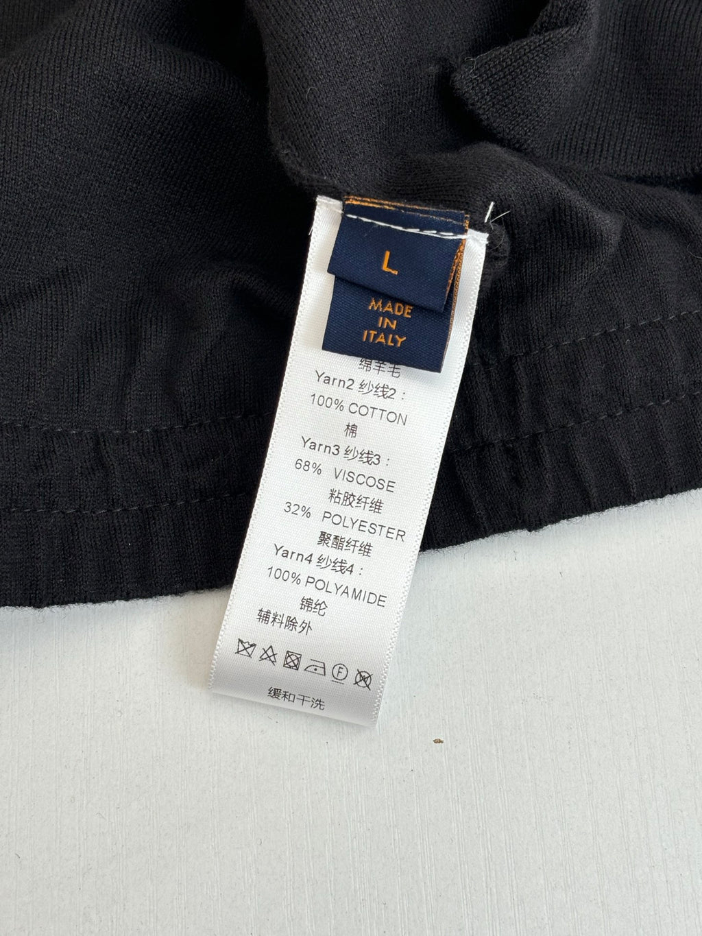 Black long garment fabric label with size L and material details