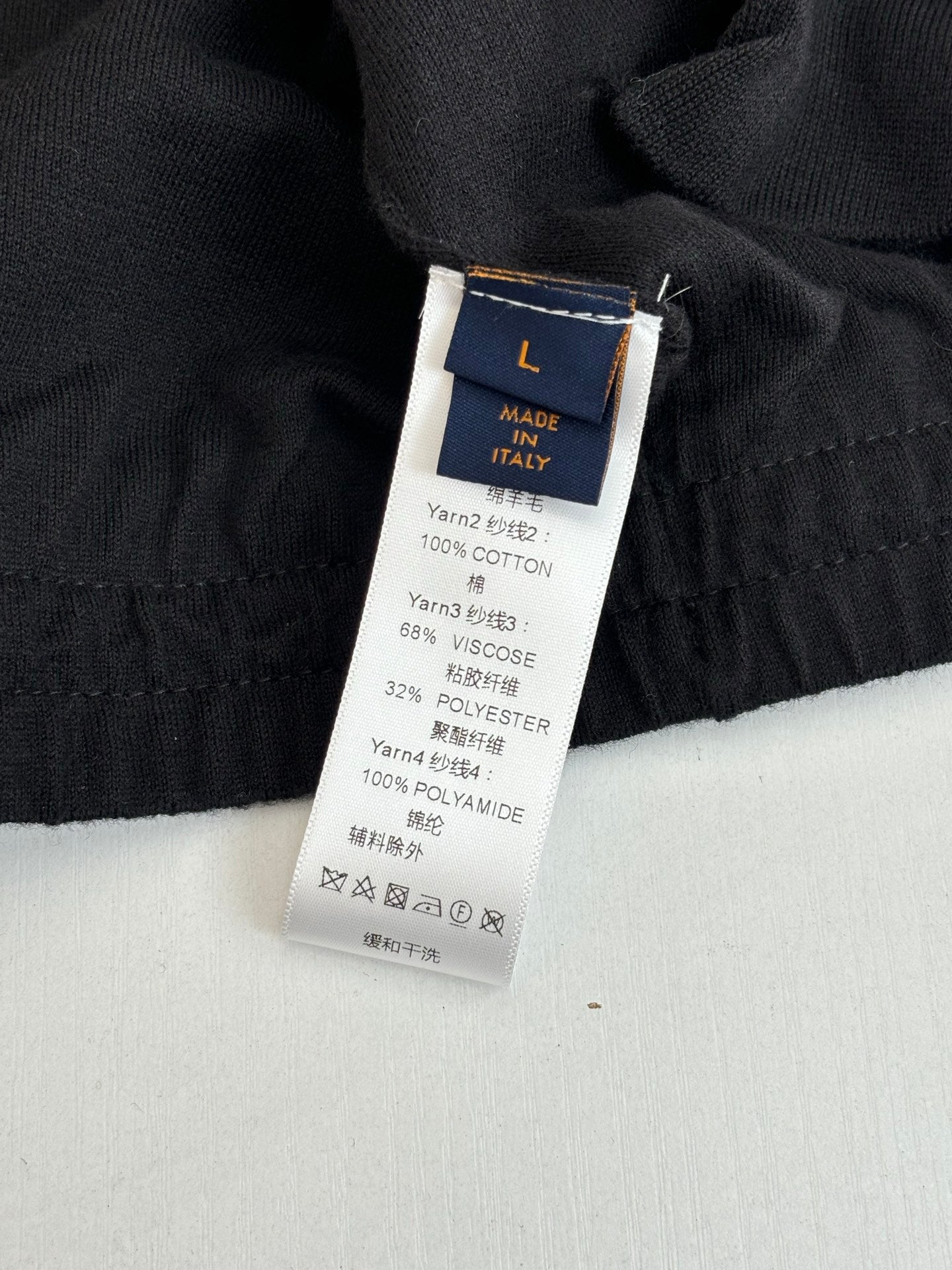 Black long garment fabric label with size L and material details