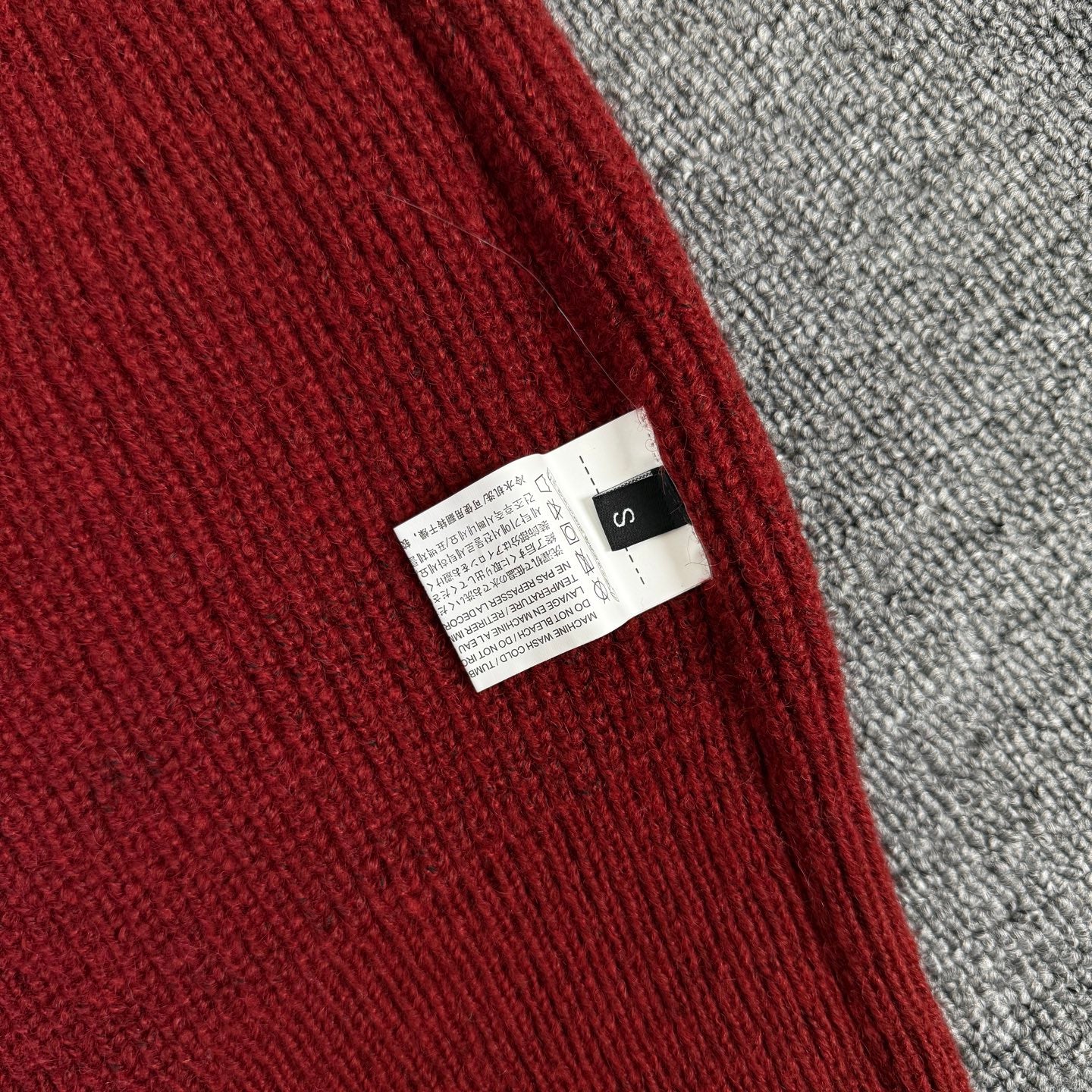 Burgundy knit hoodie interior care label near side seam