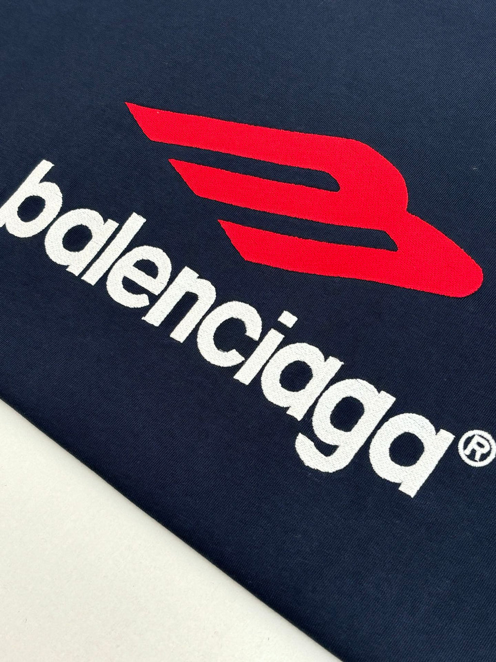 Close-up of navy long-sleeve T-shirt with Balenciaga wordmark and red symbol