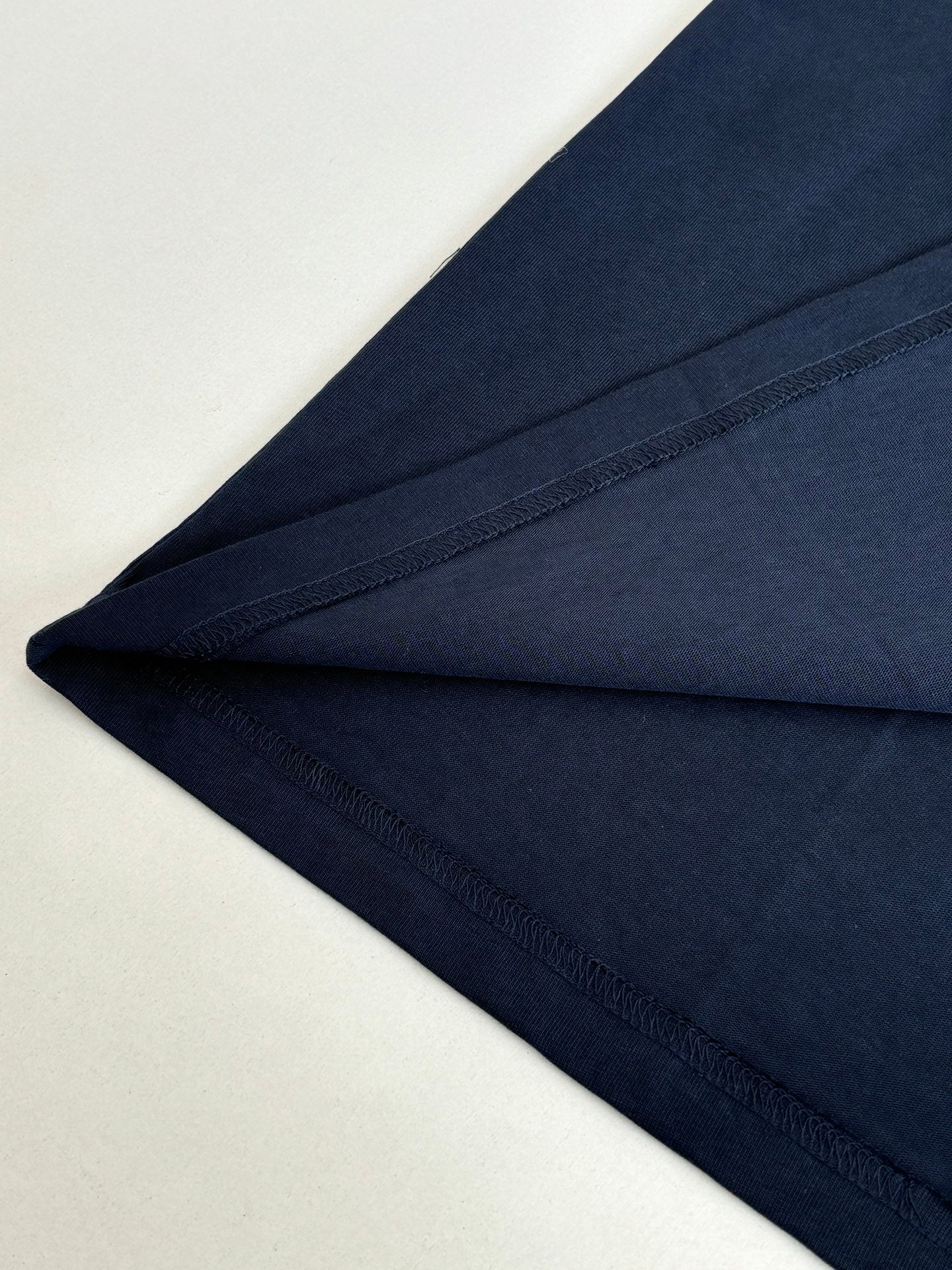 Navy long-sleeve T-shirt fabric close-up with stitched hem and sleeve edge