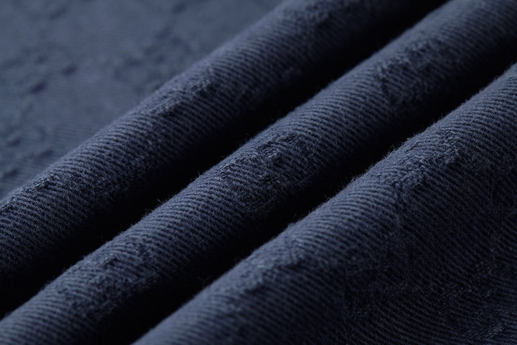 Navy jacquard fabric closeup with fine diamond pattern and soft gradient