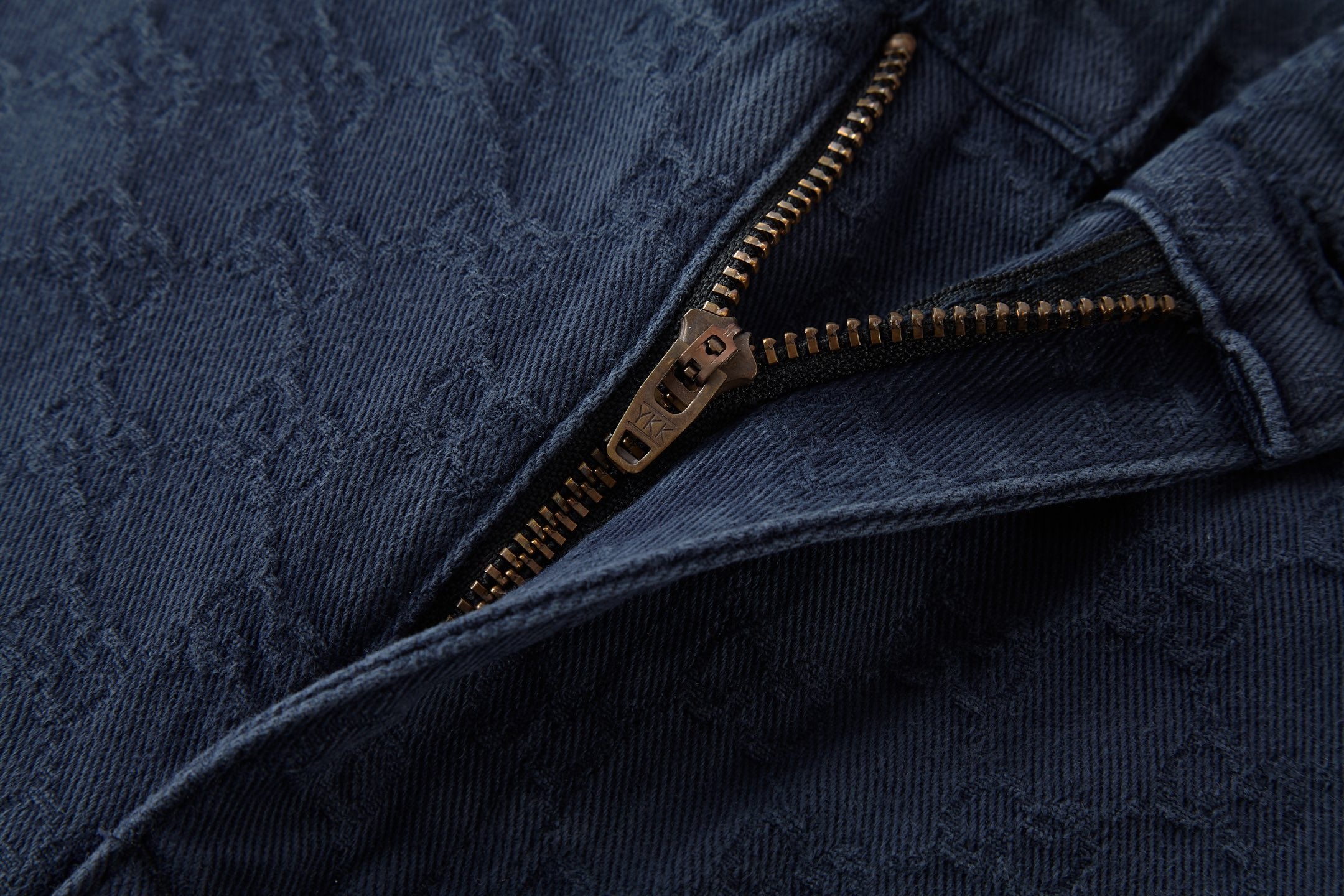 Navy jeans pocket with gold-tone zipper and jacquard fabric texture