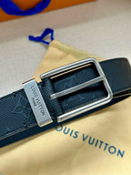 Louis Vuitton belt close-up with silver buckle on dark navy embossed strap and label.