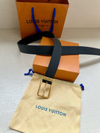 Louis Vuitton belt with gold-tone buckle on dark navy embossed strap, styled with pouch.