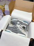 Gray low-top sneakers with white laces, blue-trim sole, and white star logo