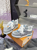 Pair of gray low-top sneakers with white laces and blue-trim outsole on box