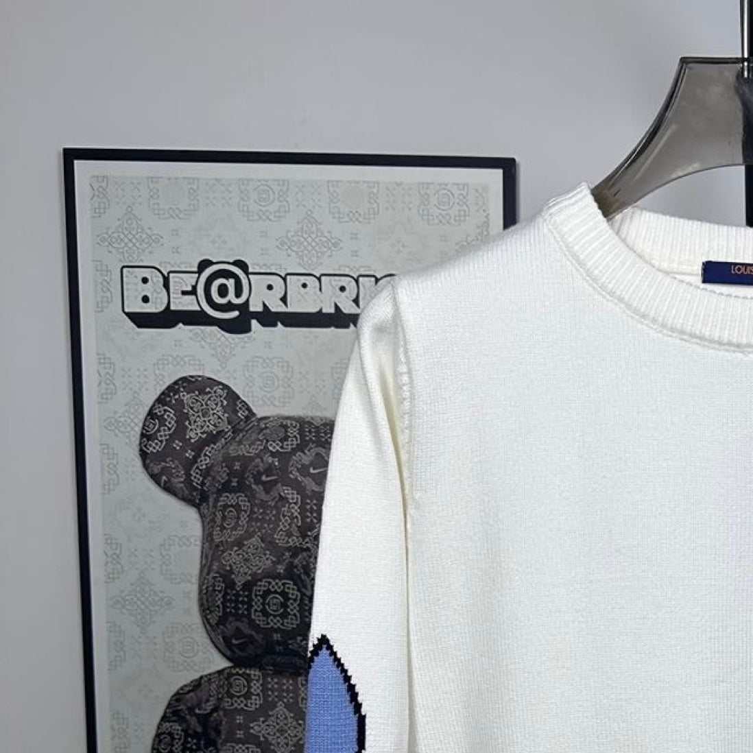 Long-sleeve knit sweater in white with ribbed crew neck and blue logo on sleeve