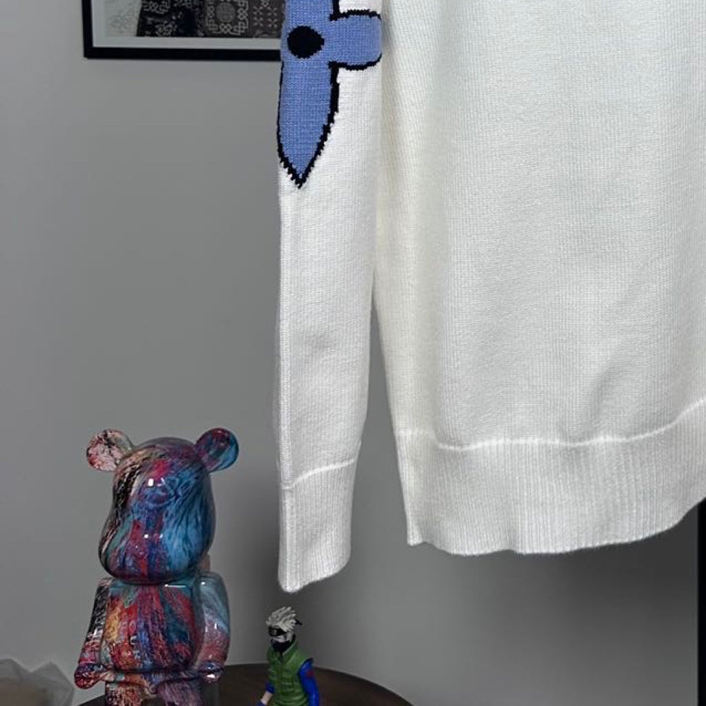 Long-sleeve knit sweater in white with blue bow-like logo detail and ribbed hem