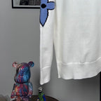 Long-sleeve knit sweater in white with blue bow-like logo detail and ribbed hem