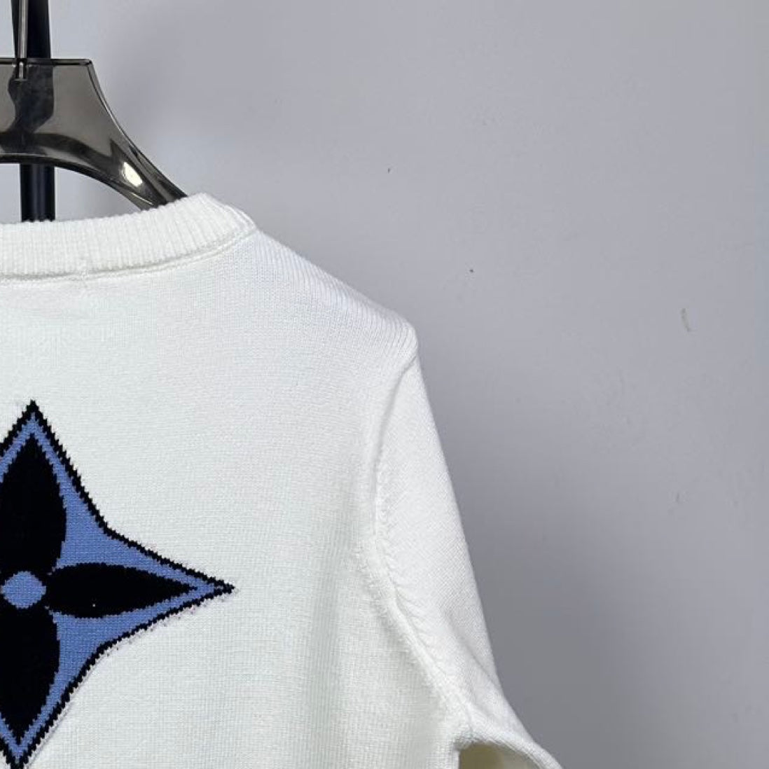 Back view long-sleeve knit sweater in white with blue star logo near shoulder