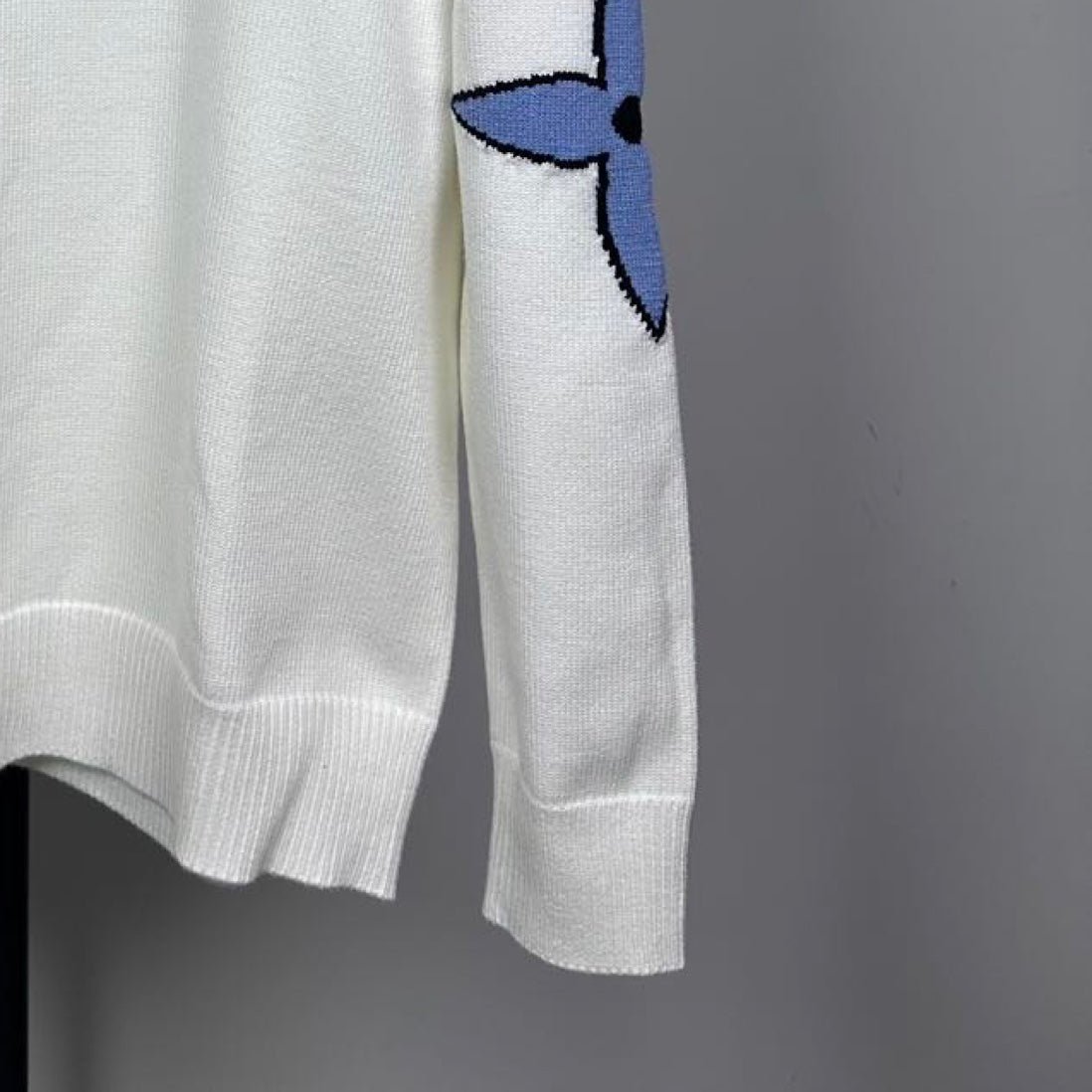 Long-sleeve knit sweater in white with blue logo on sleeve and ribbed cuffs