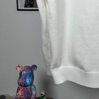 Long-sleeve knit sweater in white with ribbed hem and side drape