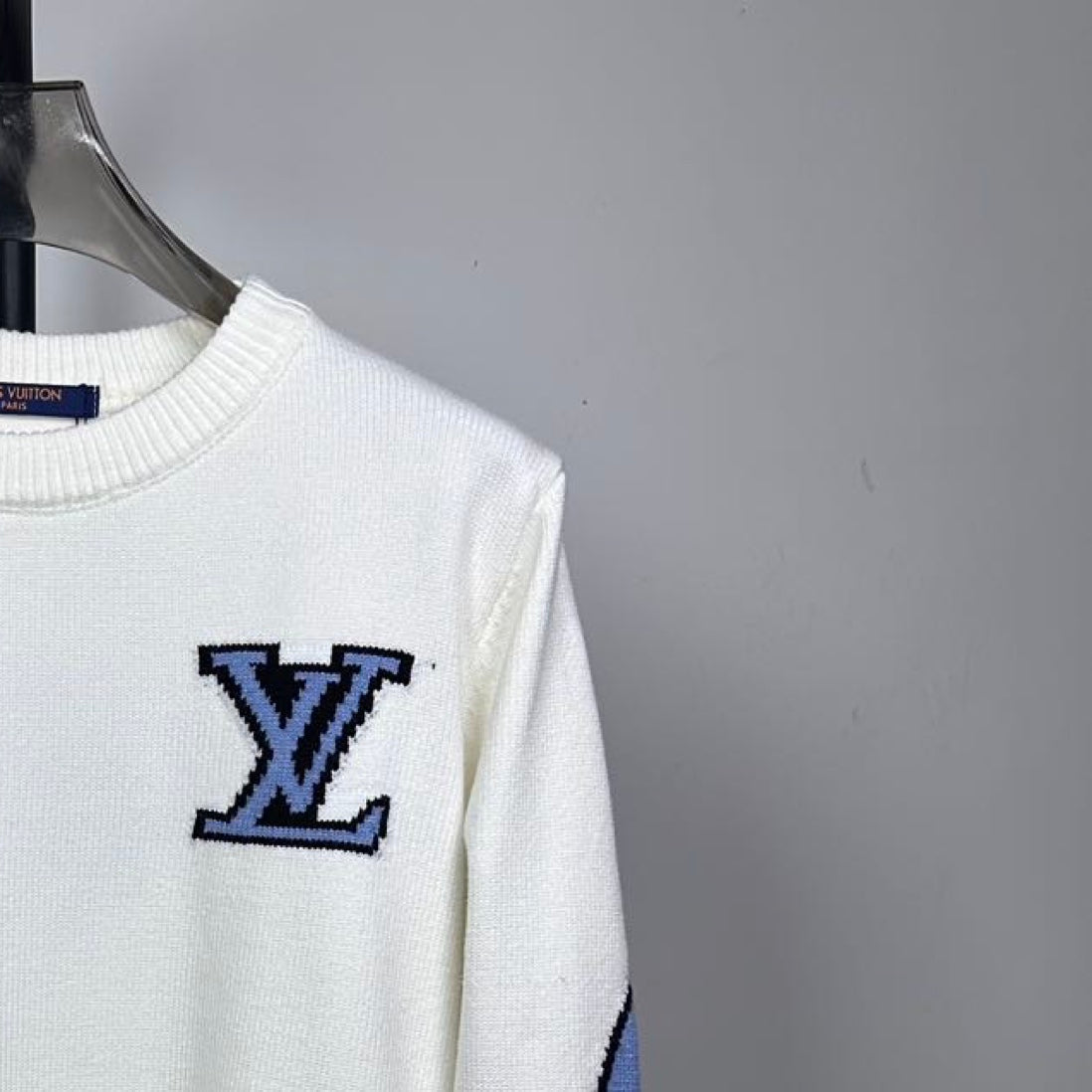 Long-sleeve knit sweater in white with blue logo patch on the chest