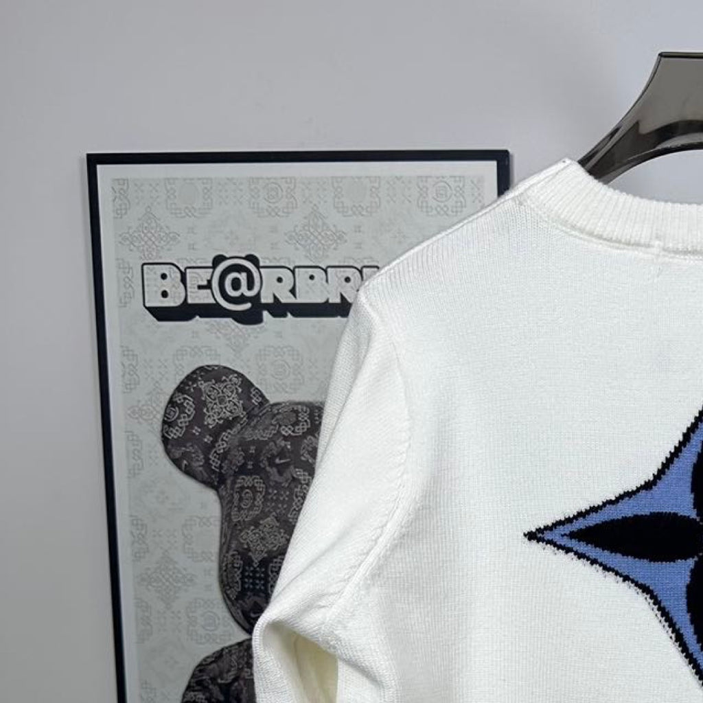 Shoulder view of long-sleeve knit sweater in white with blue star logo detail