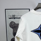 Shoulder view of long-sleeve knit sweater in white with blue star logo detail