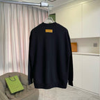Black long-sleeve crewneck sweatshirt on hanger with yellow back tag