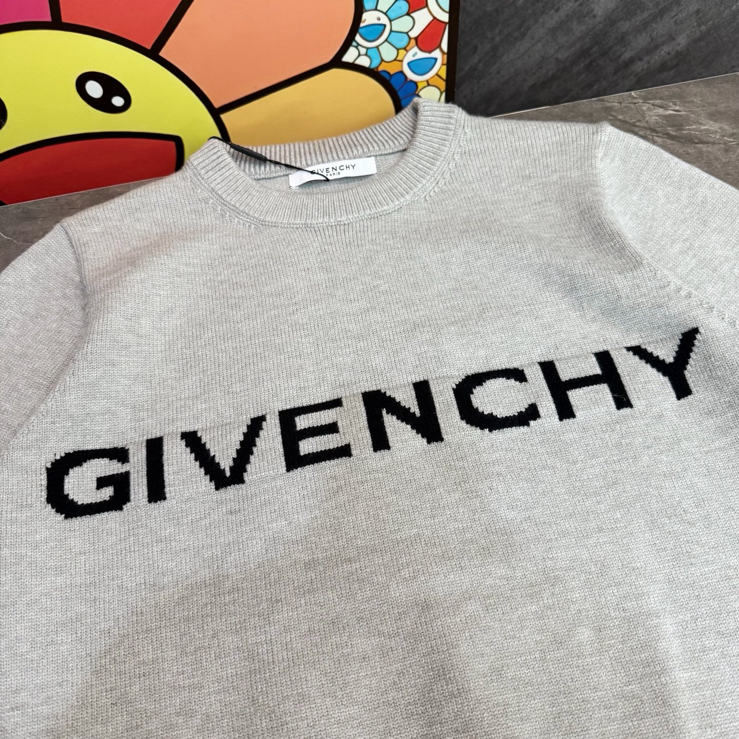 Light gray sweatshirt with large black GIVENCHY logo text across the chest
