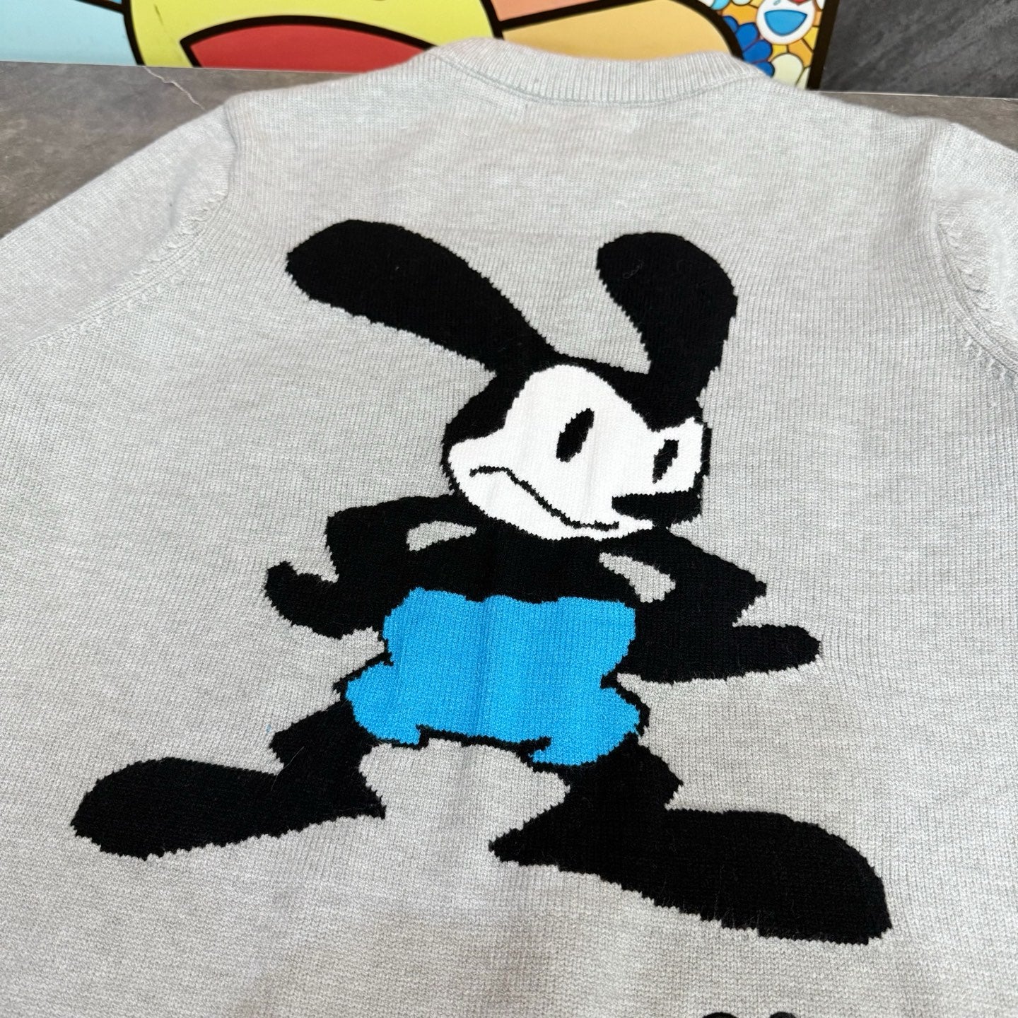Light gray sweatshirt with black Mickey Mouse illustration in blue shorts on the back