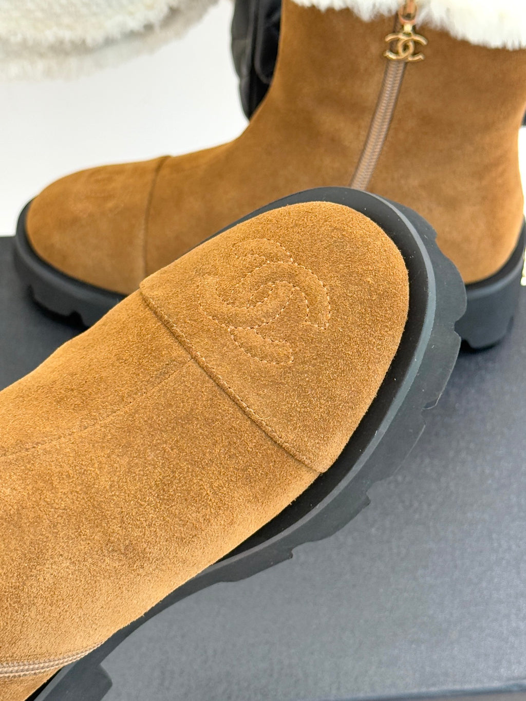 Tan suede boot with white faux-fur cuff and stitched curved toe panel.