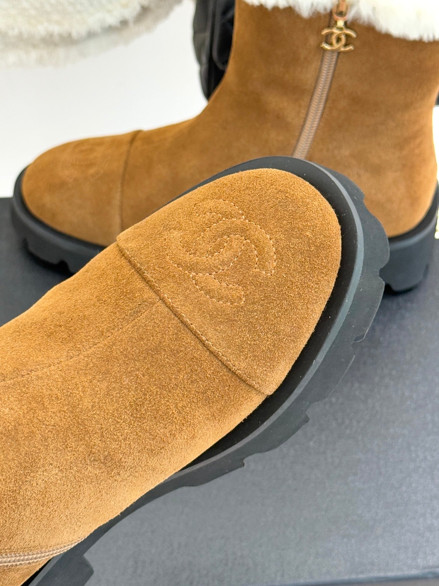Tan suede boot with white faux-fur cuff and stitched curved toe panel.