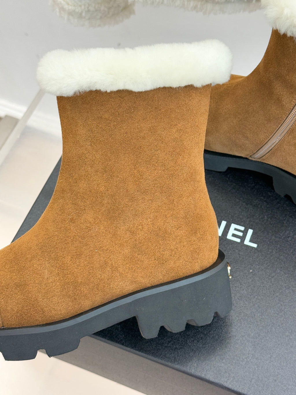 Tan suede boot with white faux-fur trim and black lug sole edge.