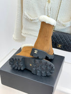 Tan suede ankle boots with black lug outsole and side zipper; white cuff visible.