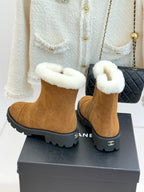 Tan suede ankle boots with white faux-fur cuffs and black logo heel detail.