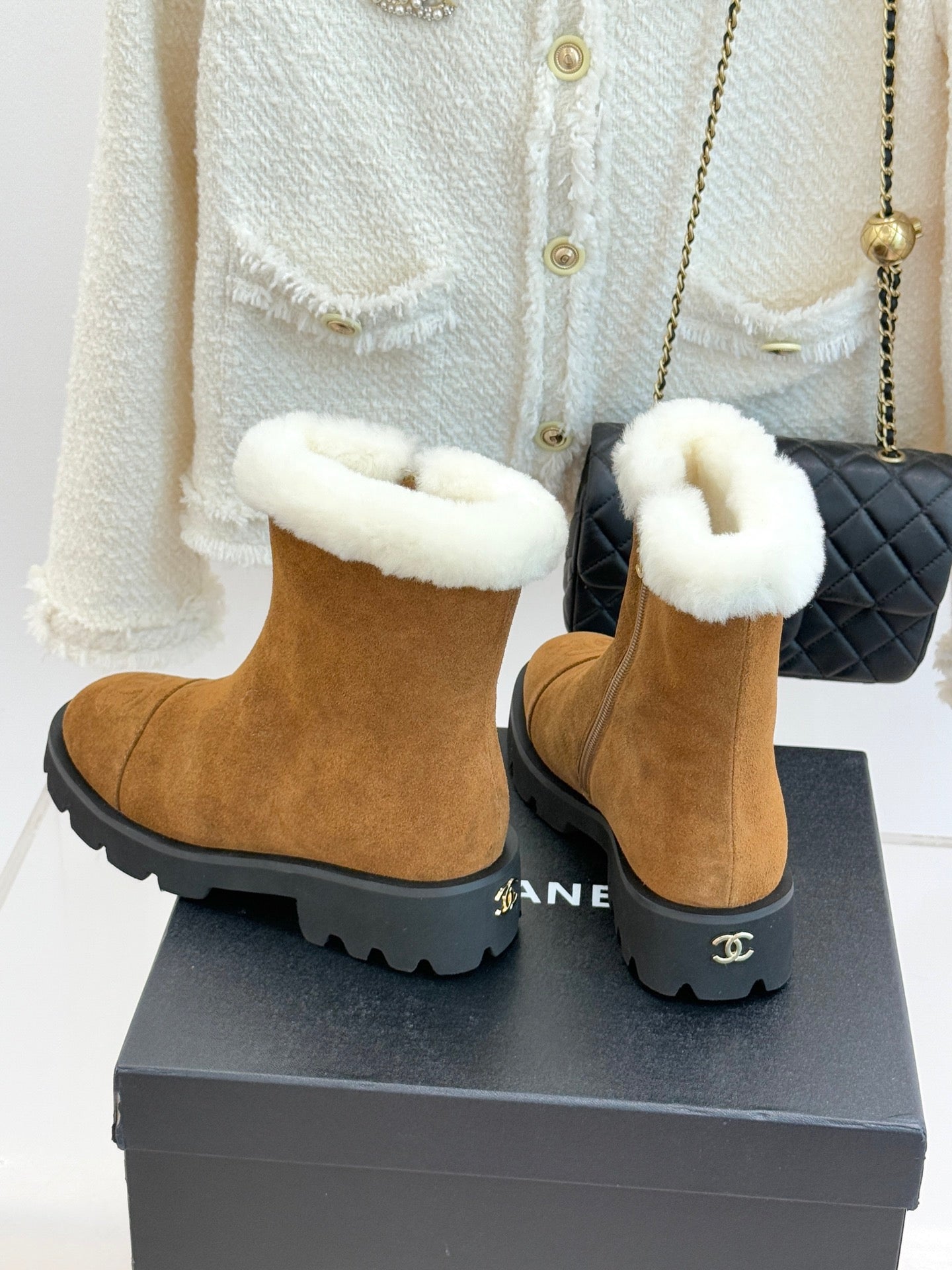 Tan suede ankle boots with white faux-fur cuffs and black logo heel detail.