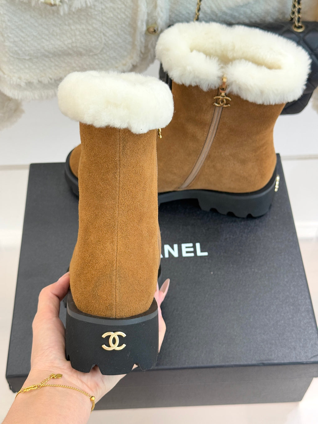 Tan suede ankle boots with white faux-fur cuffs and black logo heel detail.