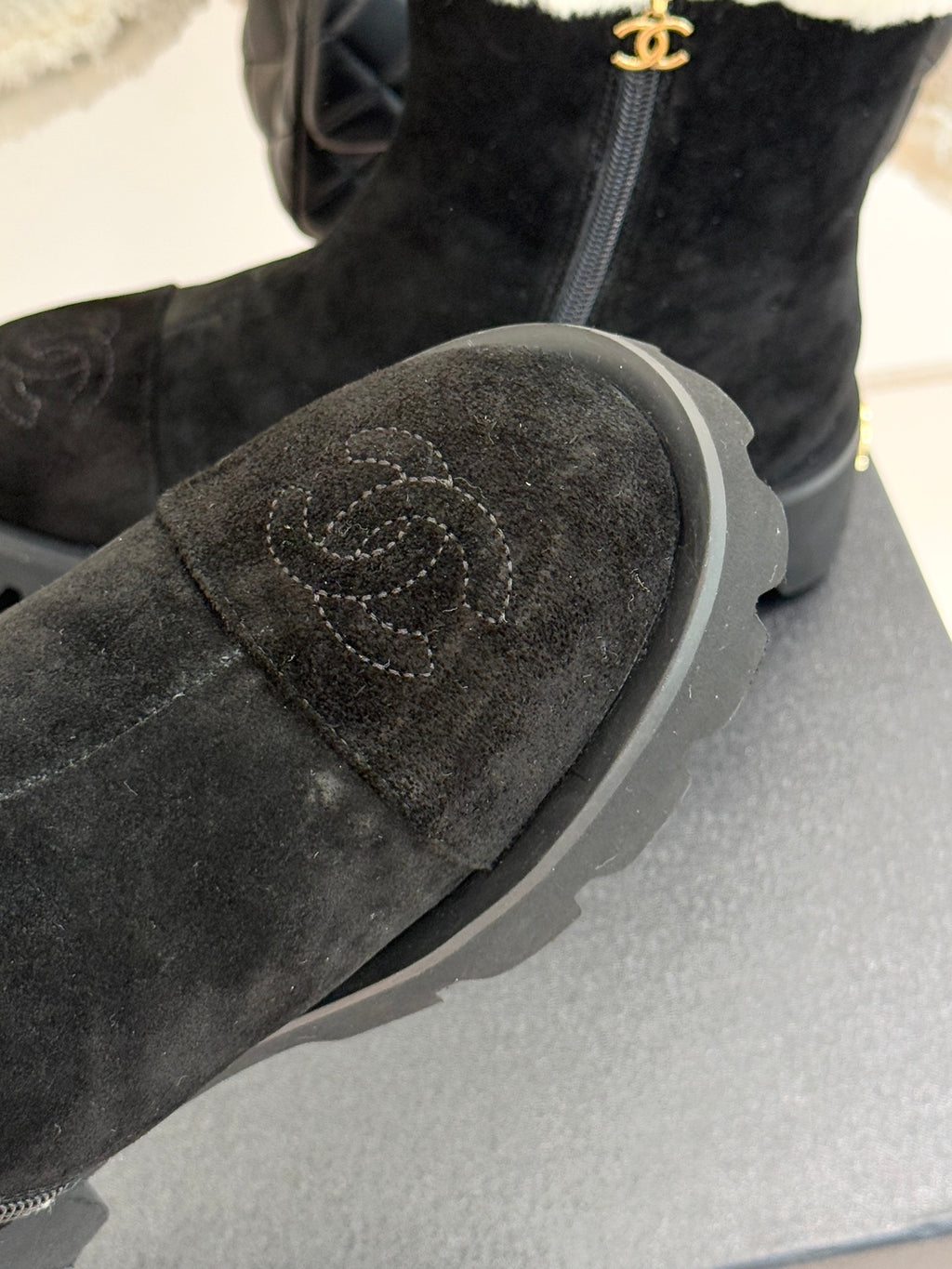 Black suede ankle boot with embossed heart-like logo on toe and gray lug sole