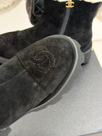 Black suede ankle boot with embossed heart-like logo on toe and gray lug sole