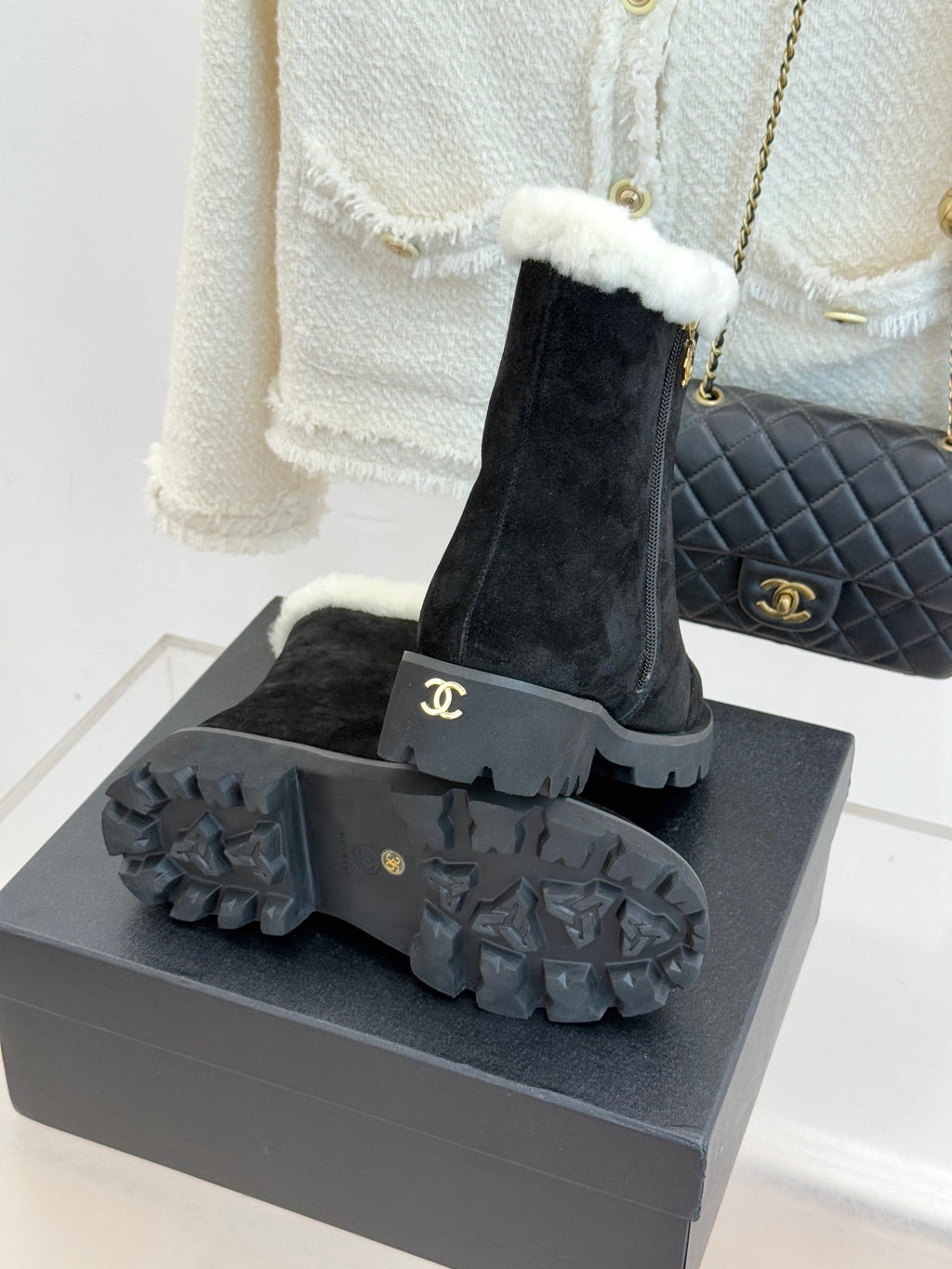 Black suede ankle boots with textured star-like gray sole and white shearling cuff