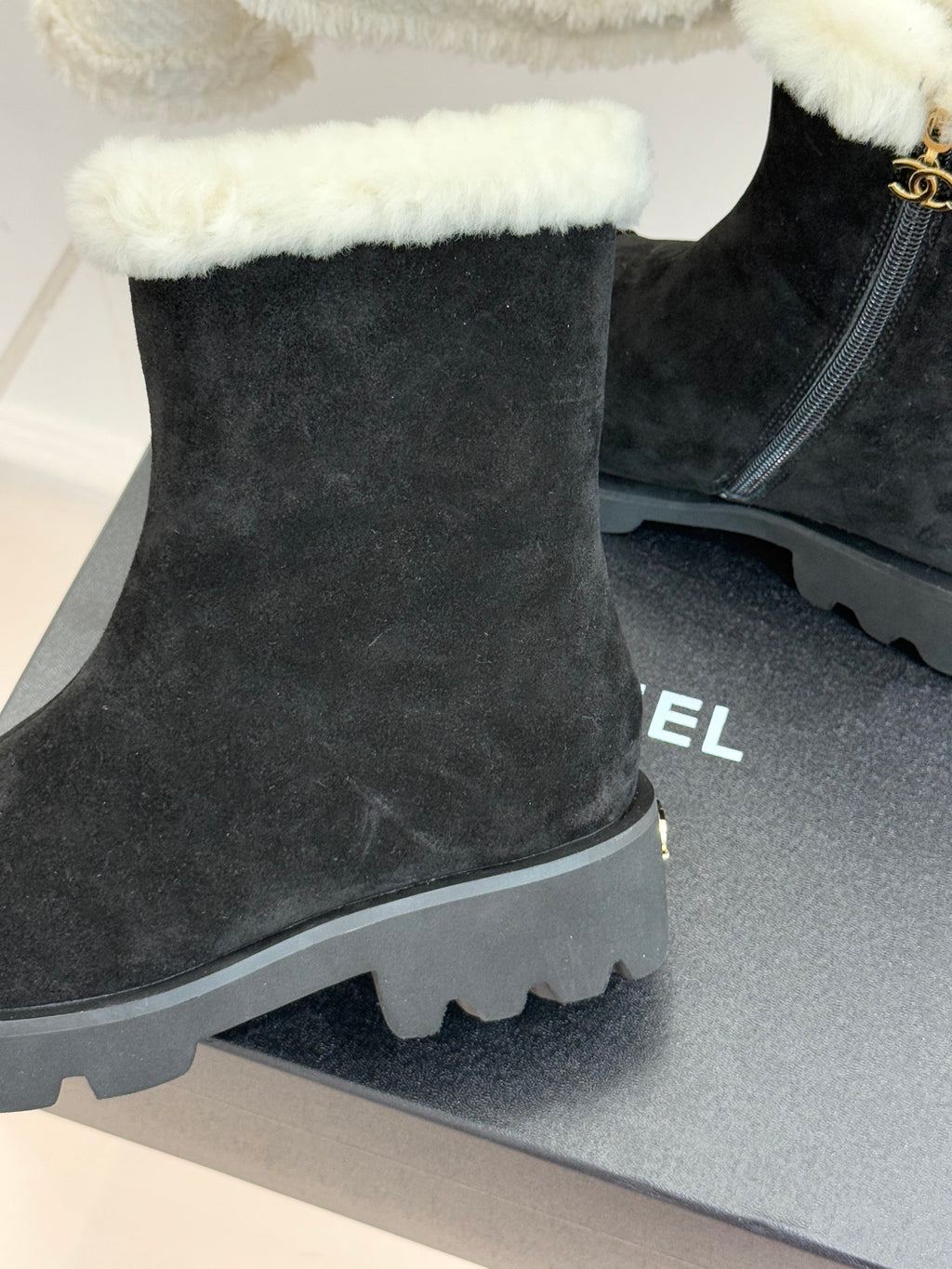 Black suede ankle boots with elastic side panel, white shearling cuff, lug sole