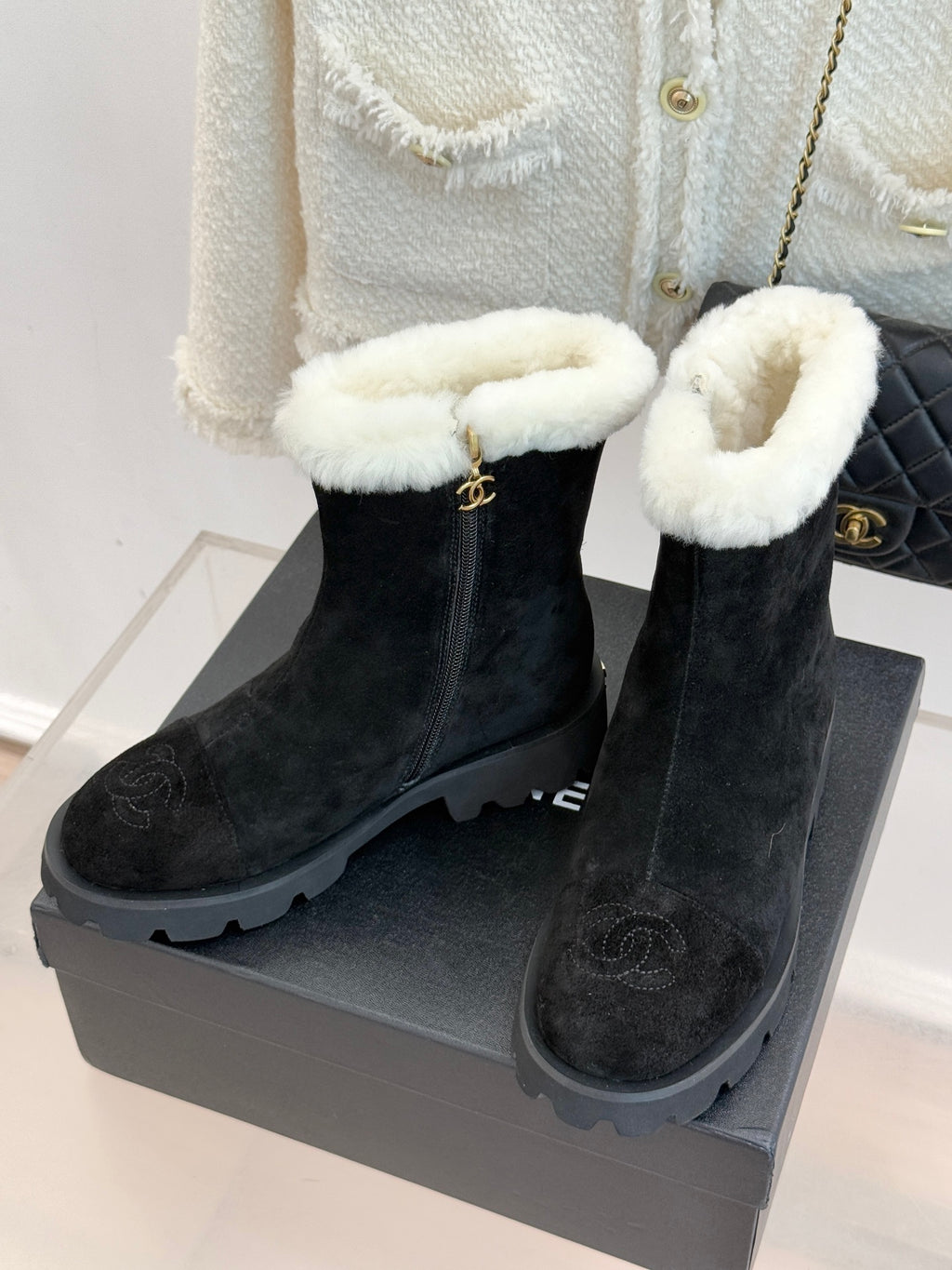 Black suede ankle boots with white fur trim, side zip, and chunky lug sole