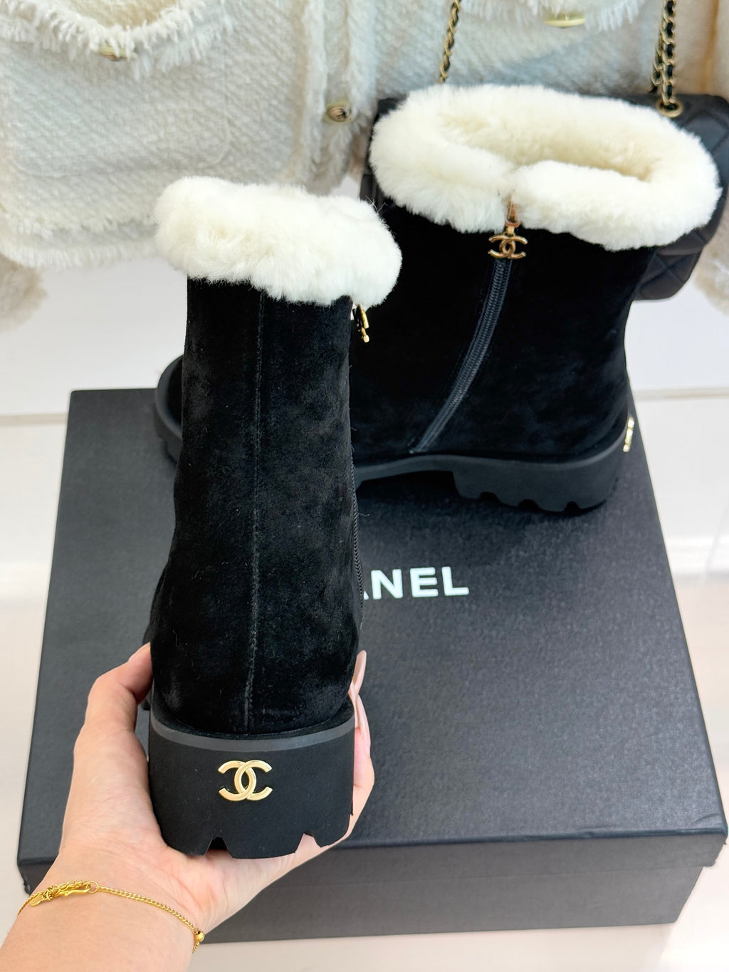 Black suede ankle boots with white shearling cuffs and side zipper, near box