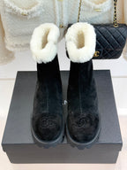 Pair of black suede ankle boots with white fur cuffs and embossed logo on shaft
